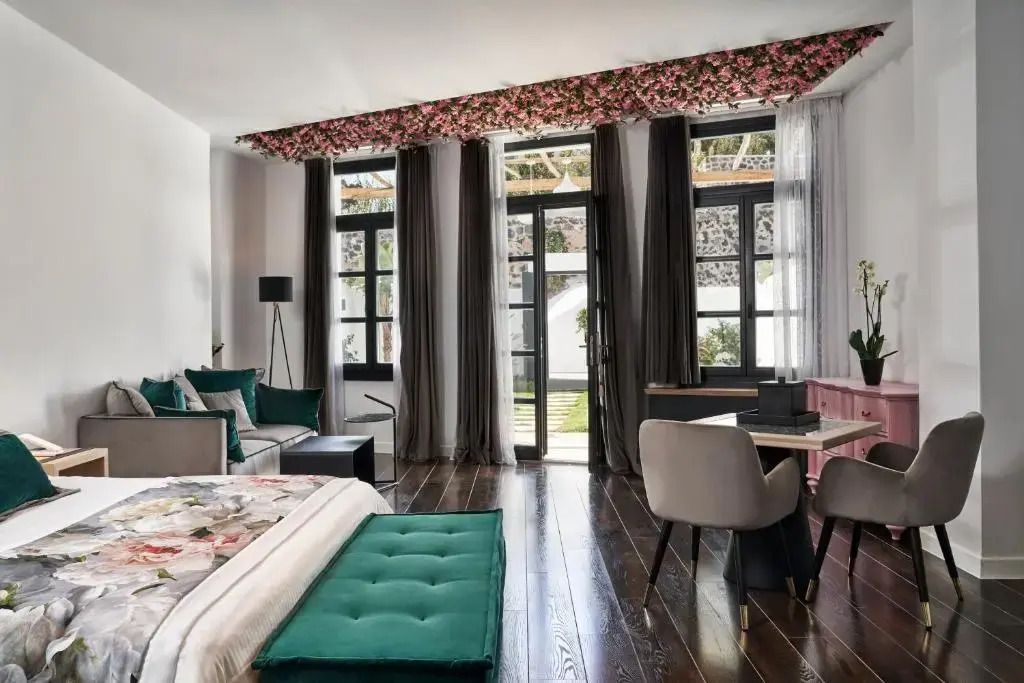 Elegante Suite mit großen Fenstern, dunklen Holzböden und üppigen Vorhängen.