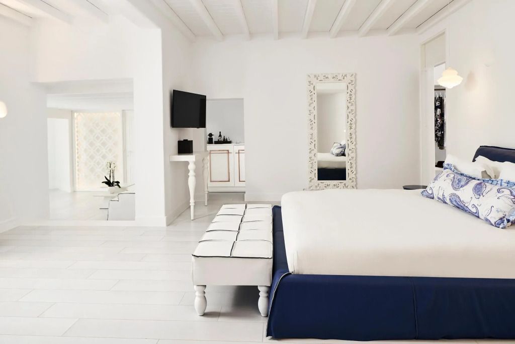 Weißes Zimmer mit Bett, Spiegel und moderner Dekoration.