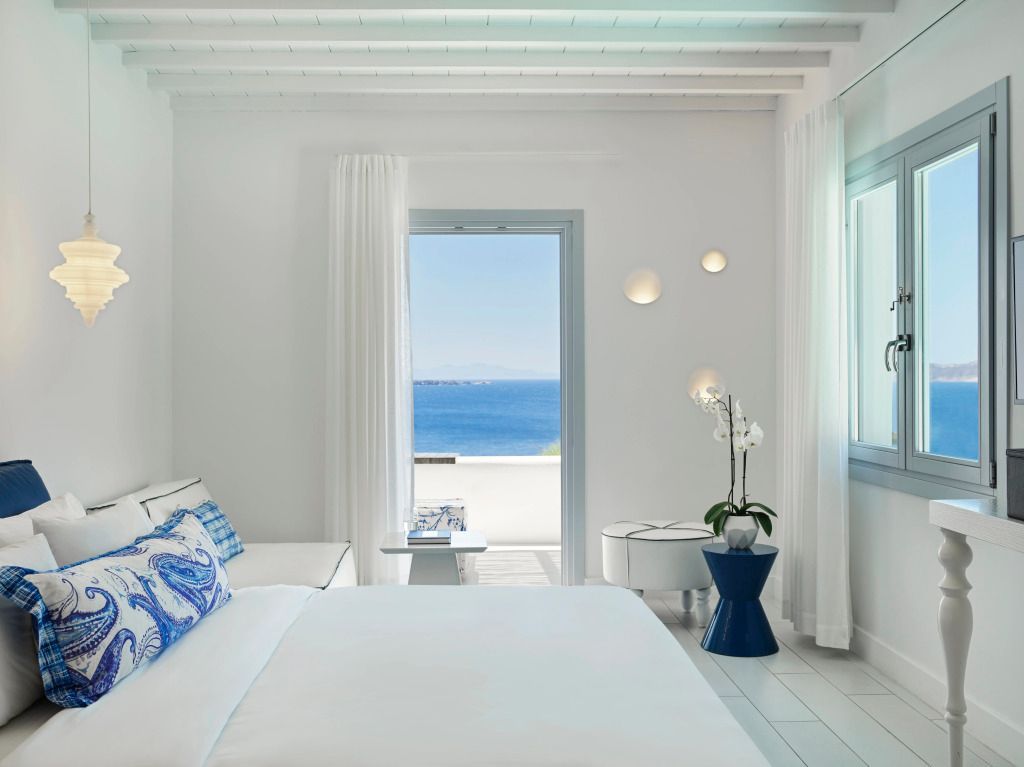 Helles Schlafzimmer mit Doppelbett und Meerblick. Moderne Einrichtung in Weiß und Blau.