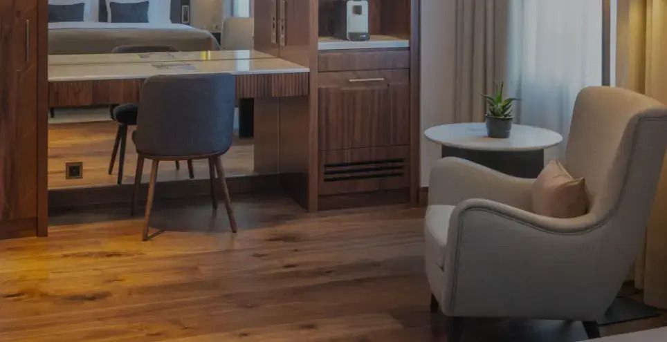 Zimmer mit Holzfußboden, modernem Schreibtisch und Lounge-Stühlen.