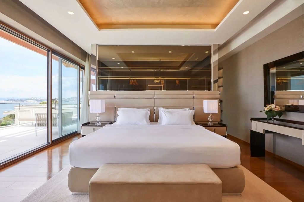 Luxuriöses Schlafzimmer mit elegantem Doppelbett und großzügigem Balkon mit Meerblick.