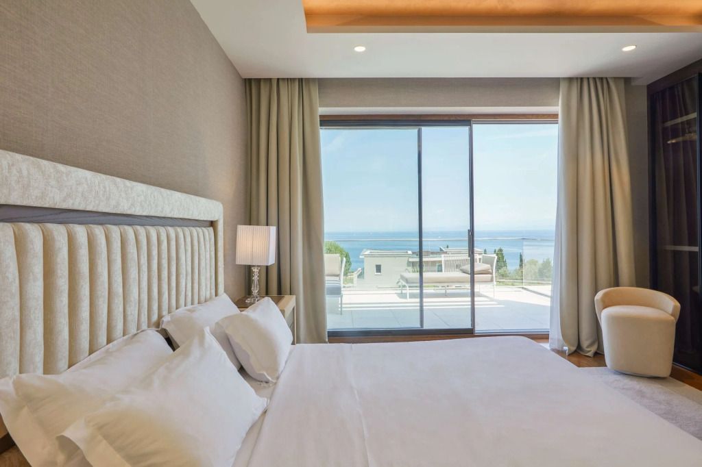 Schlafzimmer mit luxuriösem Bett und Panoramafenster mit spektakulärem Meerblick.