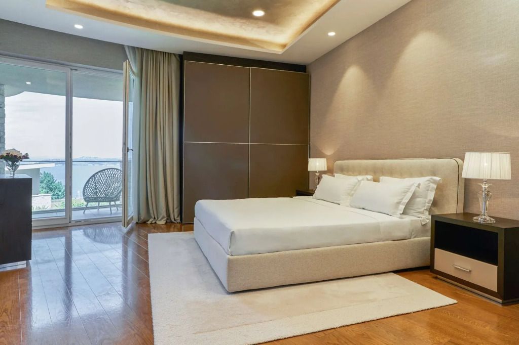 Geräumiges Schlafzimmer mit modernem Design, großem Bett und Balkon mit Meerblick.