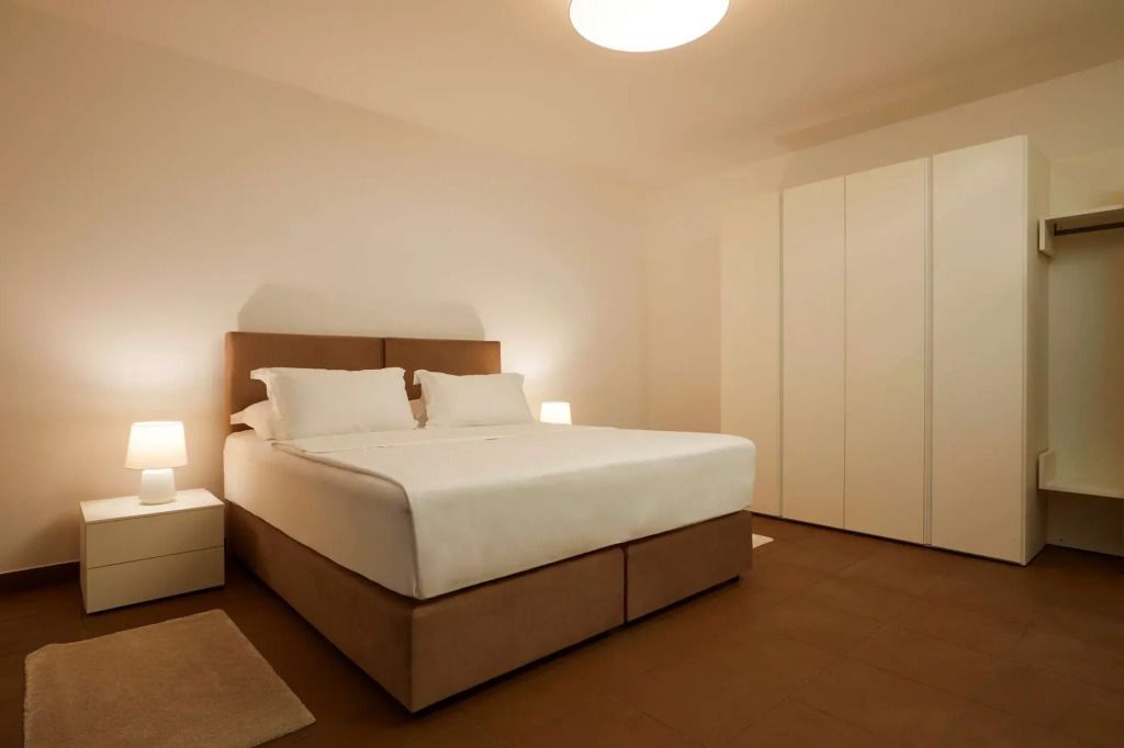 Minimalistisch eingerichtetes Schlafzimmer mit Doppelbett und warmer Beleuchtung.