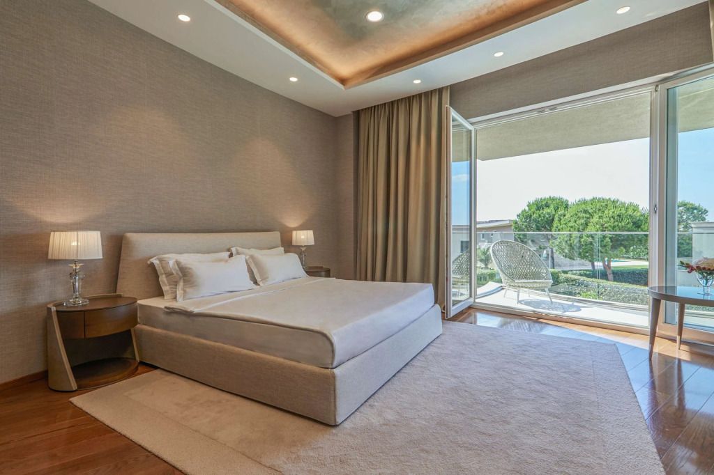 Lichtdurchflutetes Schlafzimmer mit großem Bett und Zugang zu einer Terrasse mit Gartenblick.