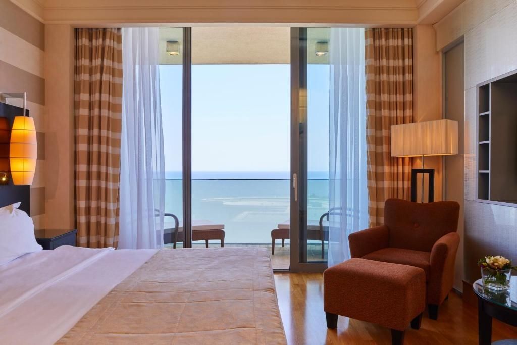 Helles Schlafzimmer mit bodentiefen Fenstern und Terrasse mit Meerblick