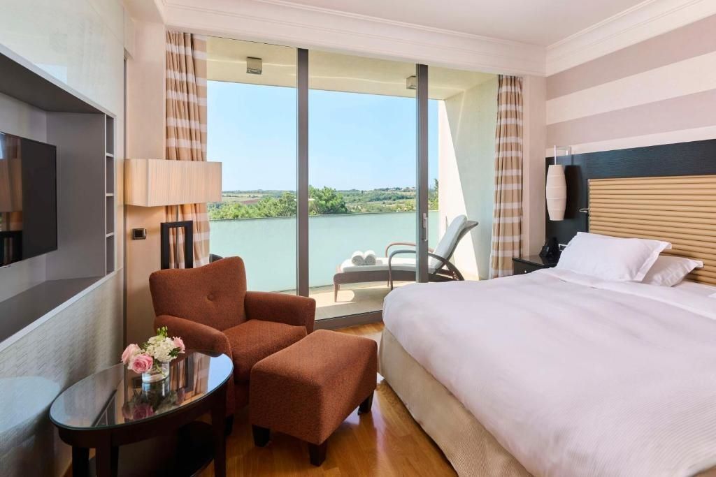 Helles Schlafzimmer mit Doppelbett und Ausblick auf Garten und Wasser.