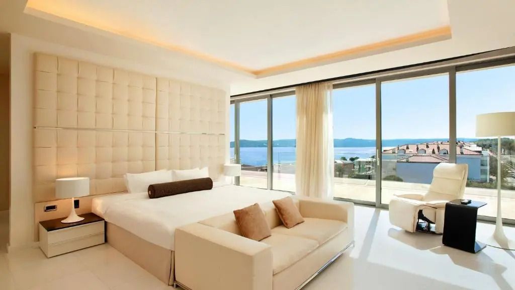 Luxuriöse Suite mit Doppelbett und Meerblick durch große Fenster