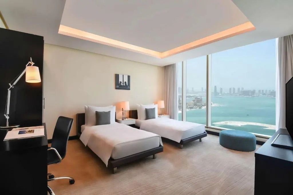 Doppelzimmer mit zwei Einzelbetten und Blick auf das Meer und die Skyline von Doha