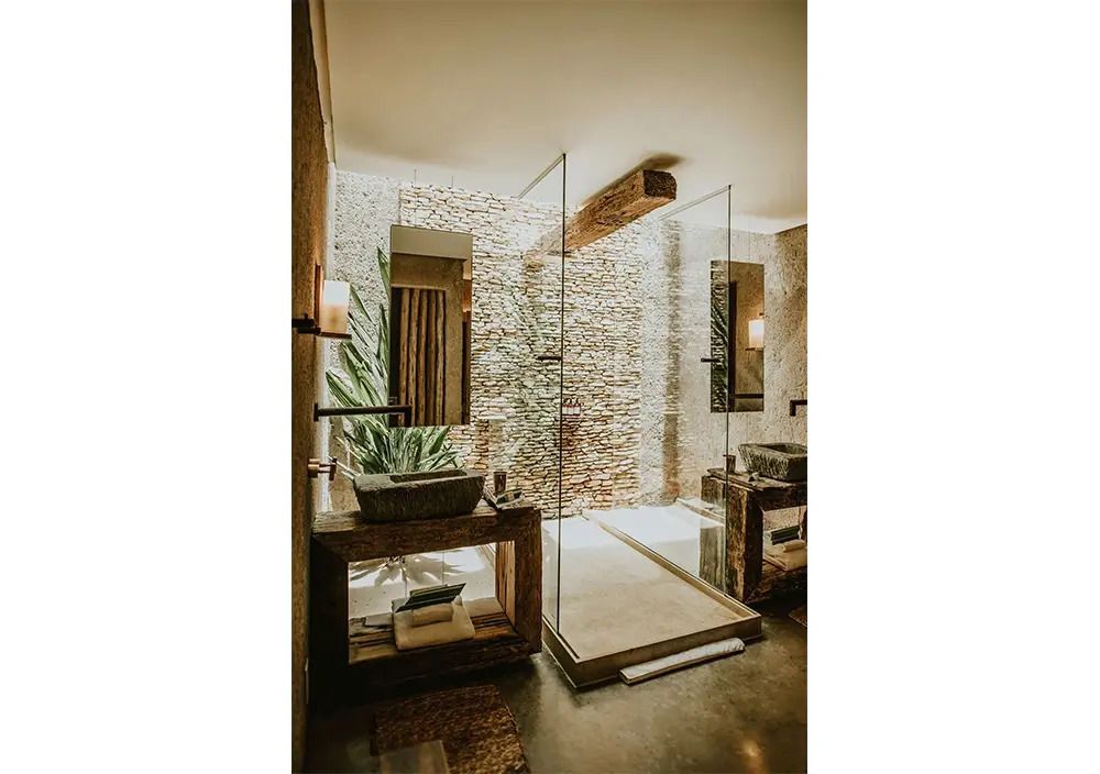 Luxuriöses Badezimmer mit Regendusche und Steinwand im Kenoa Resort