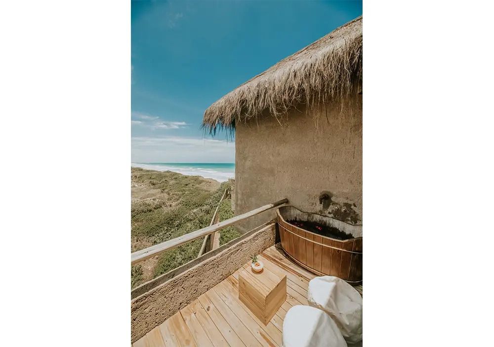 Gemütliche Terrasse mit Holzbadewanne und Blick auf Strand und Meer im Kenoa Resort