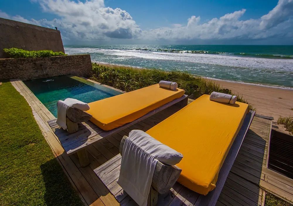 Zwei Liegestühle mit Pool und Meerblick in der Sonne im Kenoa Resort