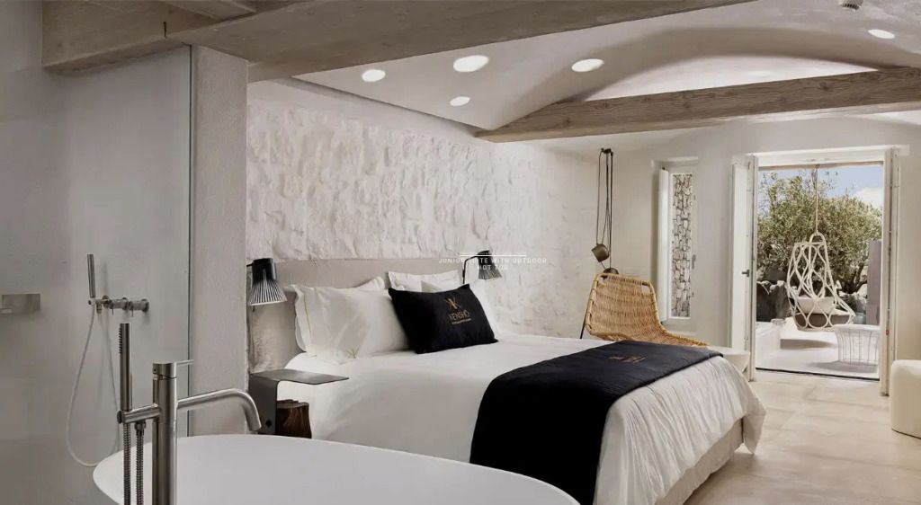 Schlafzimmer mit Doppelbett und eleganten weißen Wänden in einer Junior-Suite
