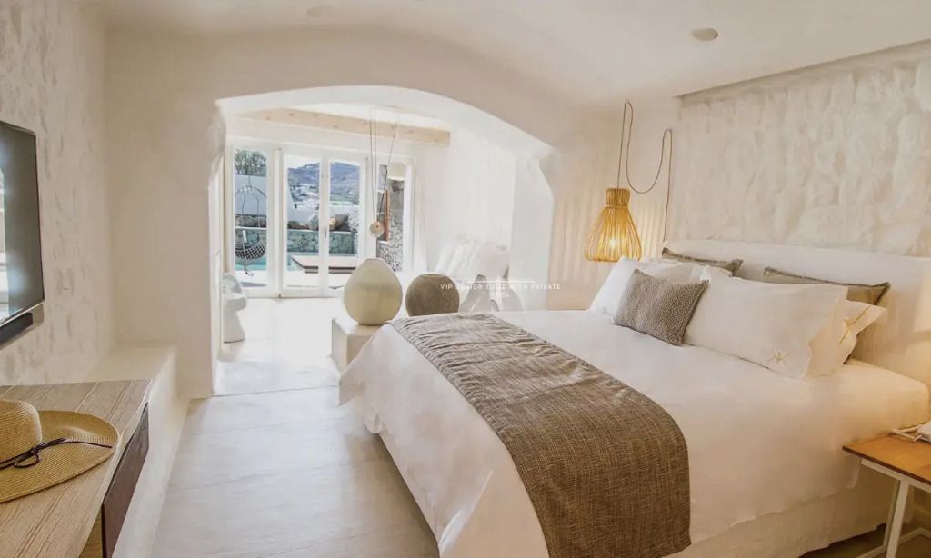 Helle Junior-Suite mit Doppelbett und stilvoller Deko. Blick auf Terrasse und Pool.
