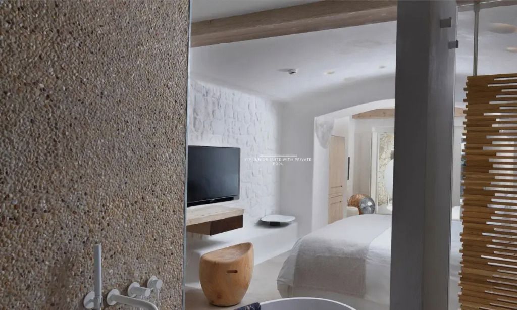 Blick auf Suite mit TV und hellem modernen Dekor von Badezimmer aus.