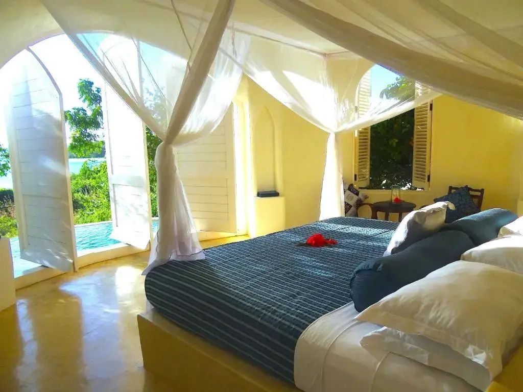 Luxuriöses Schlafzimmer in einer Villa mit Himmelbett und Ausblick auf den tropischen Garten