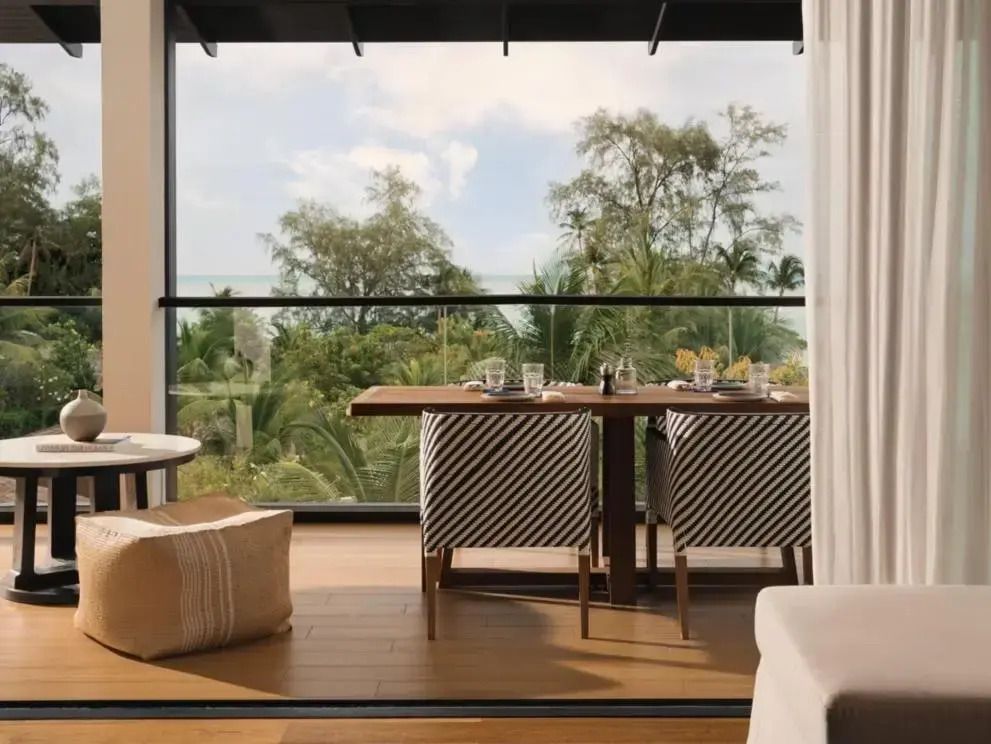Balkon der Suite mit Esstisch und Ausblick auf tropische Vegetation und Meer.