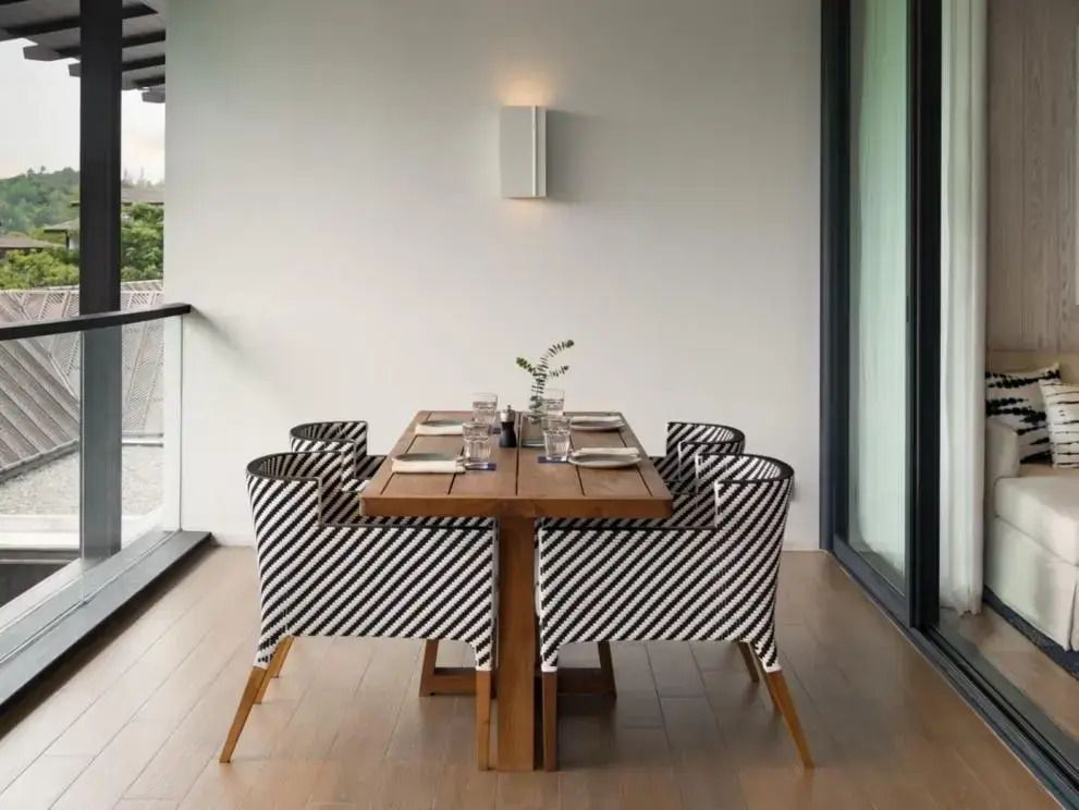 Eleganter Essbereich auf dem Balkon mit vier Stühlen und modernem Tisch.