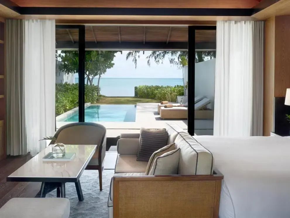 Zimmer mit Sitzbereich und direktem Zugang zum Pool mit Meerblick