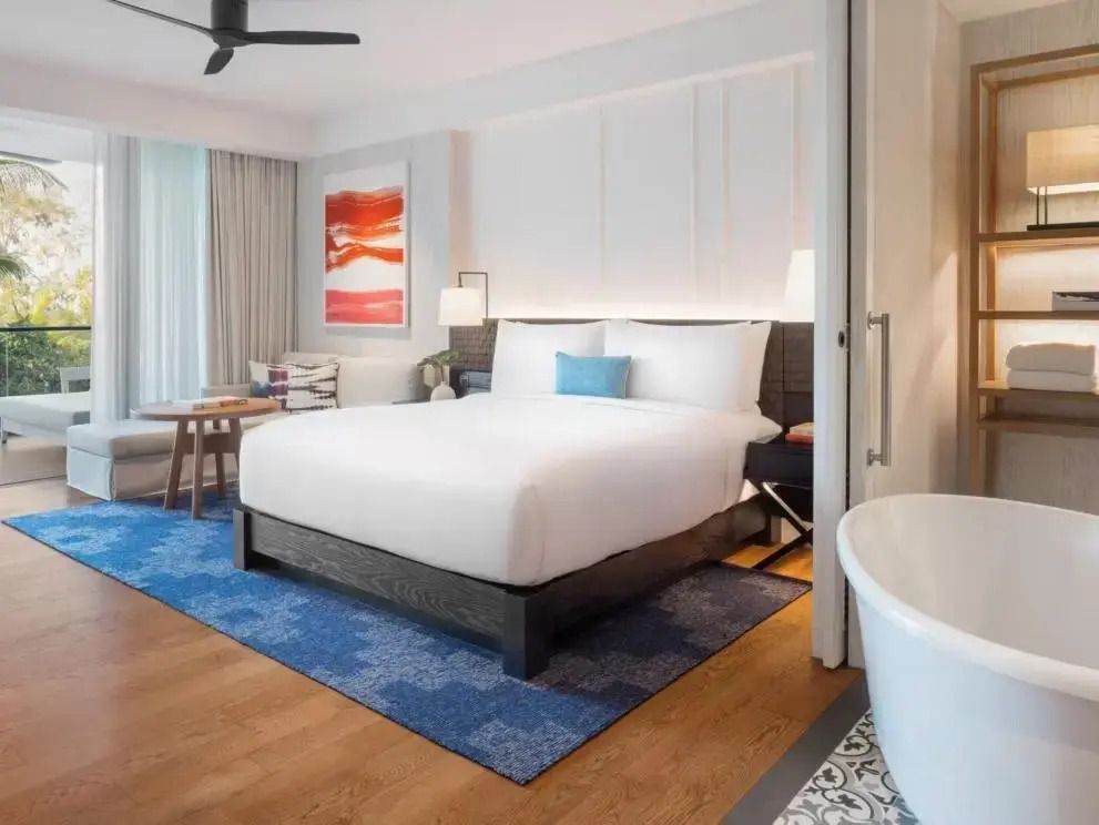 Modernes Hotelzimmer mit Doppelbett, blauer Teppich und Sitzecke