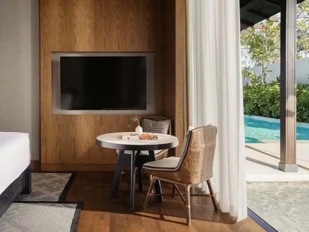 Kleiner Tisch mit Blick auf den Pool durch große Fenster.