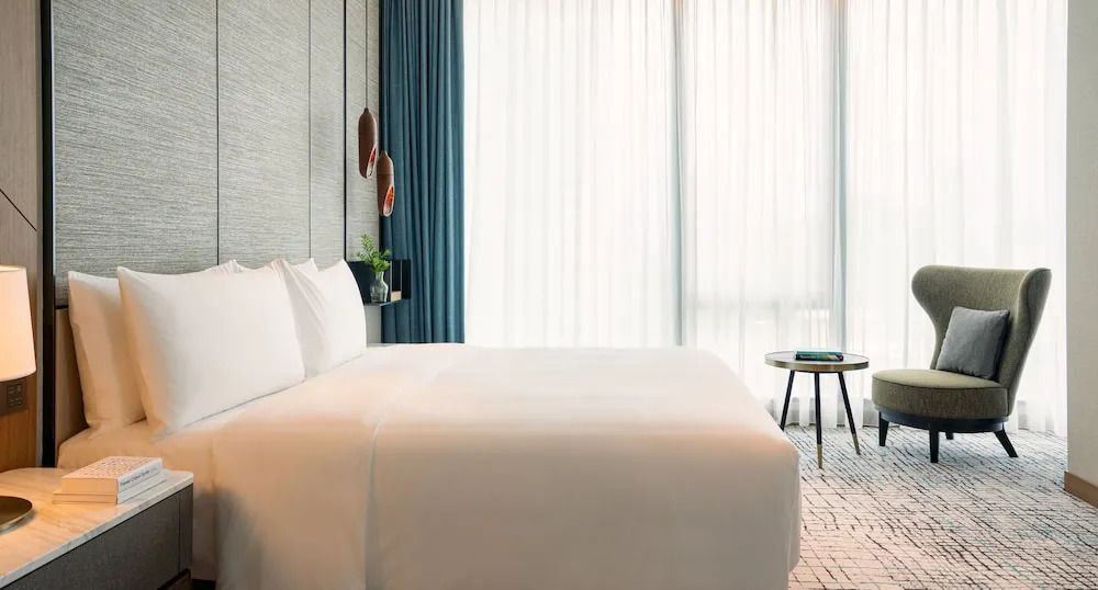 Modernes Schlafzimmer mit Doppelbett und raumhohen Fenstern in einer Junior-Suite