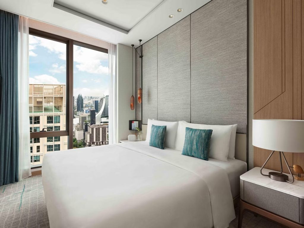 Modern eingerichtetes Studiozimmer mit Doppelbett und Stadtblick durch ein großes Fenster.