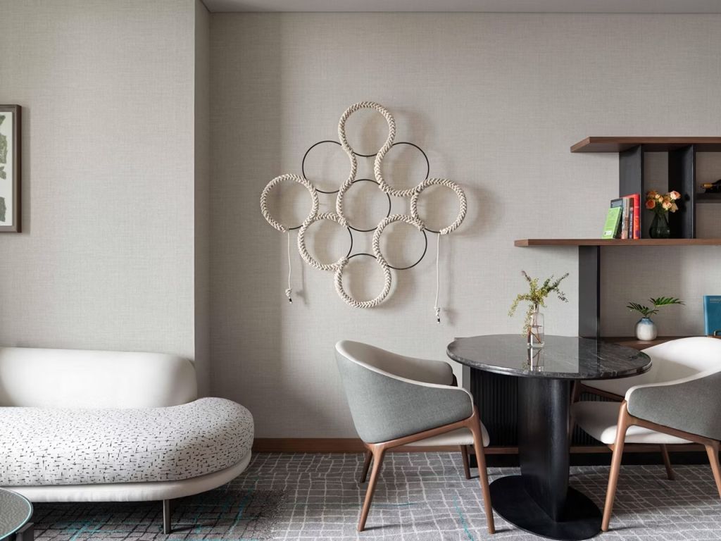 Schicke Sitzecke im Hotelzimmer mit dekorativem Wandornament und stilvollen Möbeln.