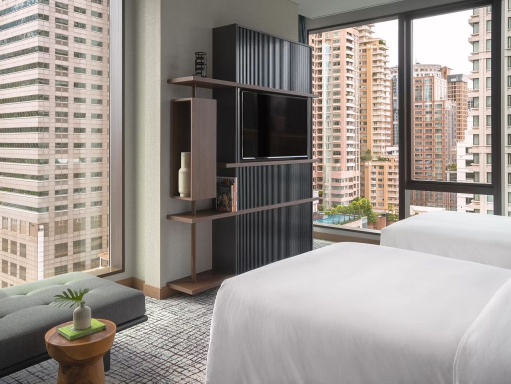 Helles Schlafzimmer in der Familiensuite mit Fernseher und Stadtblick.