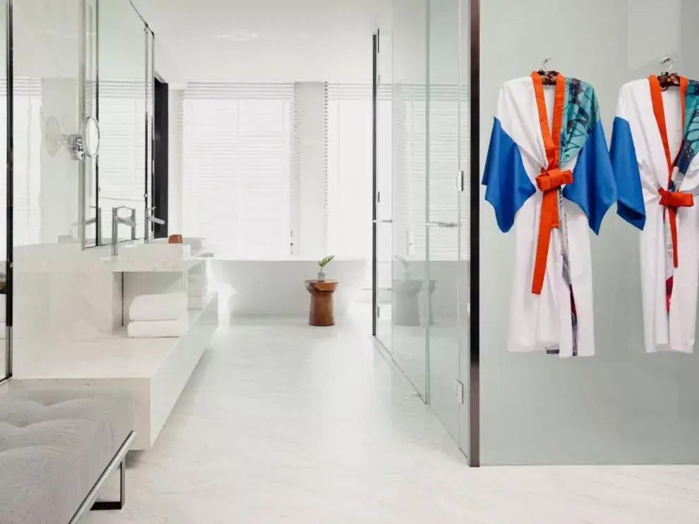 Helles Badezimmer mit Bademantel und großer Glasdusche im Kimpton Maa-Lai Bangkok