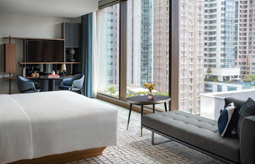Helles Hotelzimmer mit großem Fenster und Blick auf die Stadt.