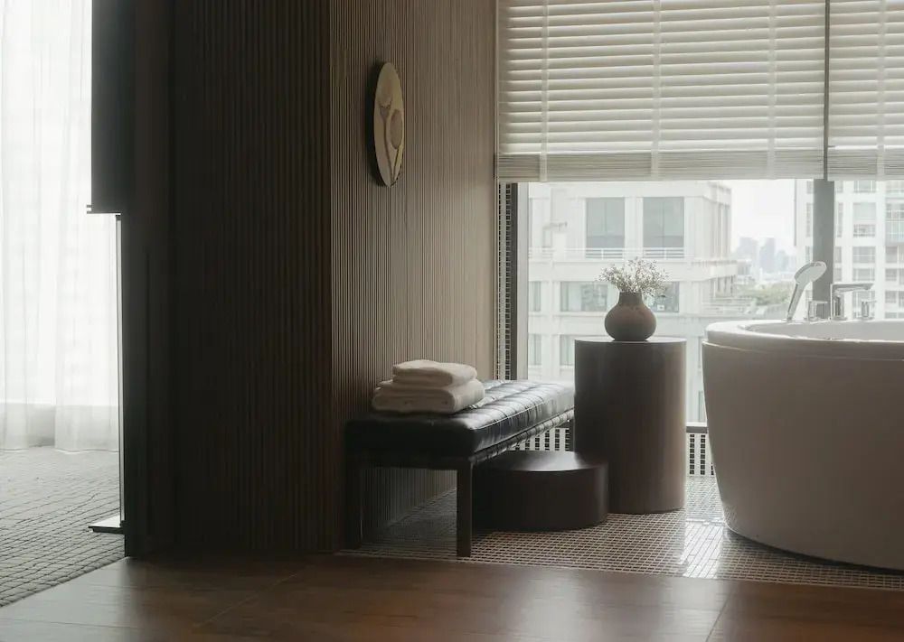 Luxusbadezimmer mit freistehender Badewanne, großer Fensterfront und stilvollen Holzelementen.