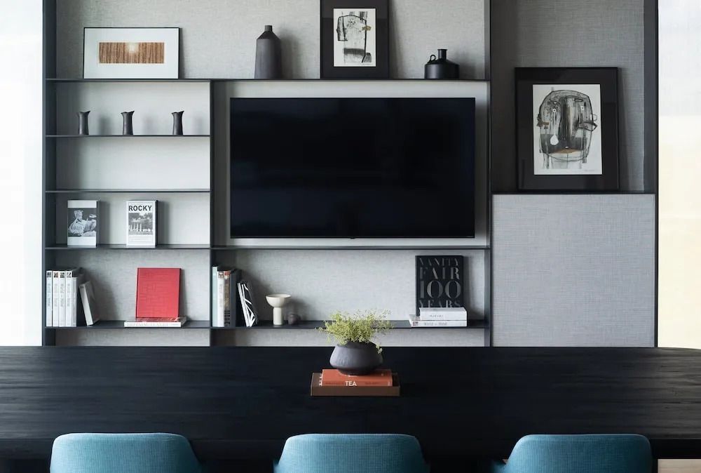 Wohnbereich mit stilvoller Wanddekoration, Bücherregal und modernem Flachbildfernseher.