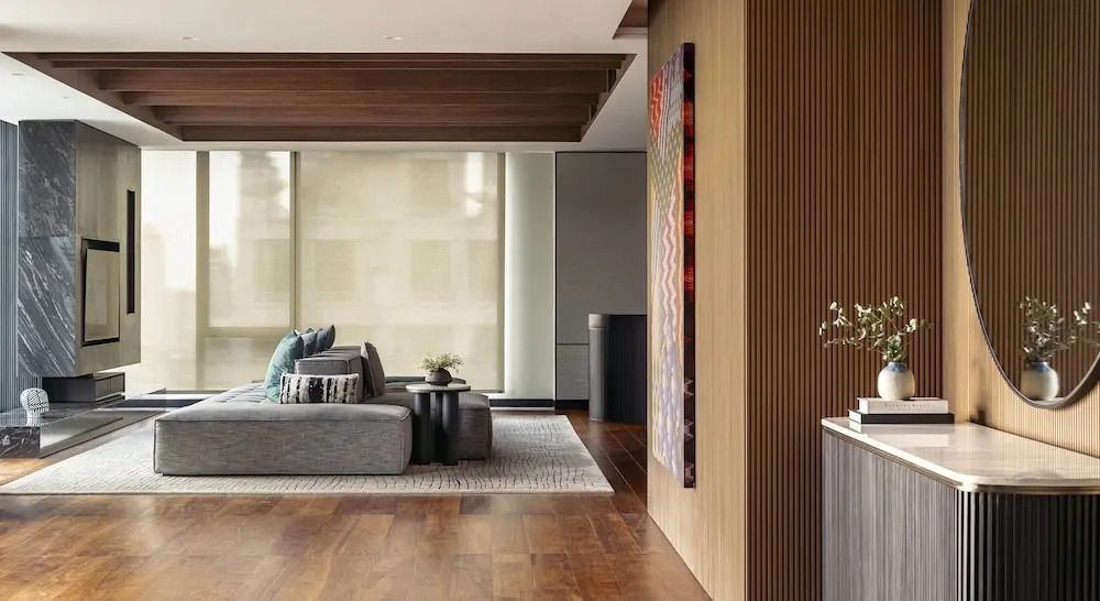 Helles Wohnzimmer mit großen Fenstern, komfortablem Sofa und eleganter Holzeinrichtung.