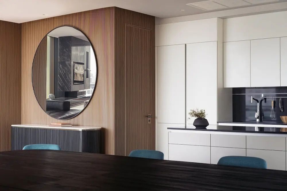 Moderne Küche mit rundem Spiegel, stilvollen Holzwänden und eleganten Einbaumöbeln.