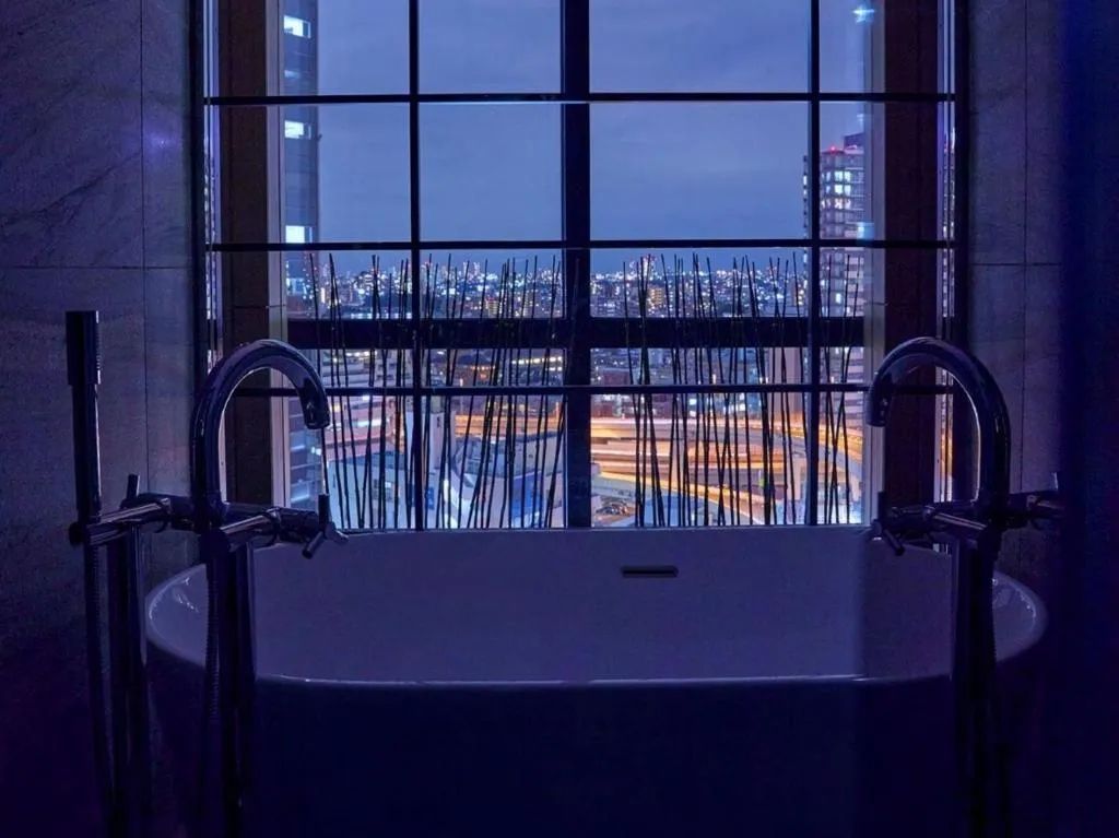 Moderne Badewanne mit Panoramablick auf die Stadt bei Nacht