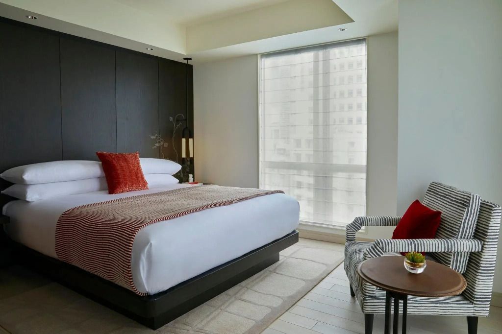 Modern eingerichtetes Hotelzimmer mit Doppelbett und großen Fenstern.