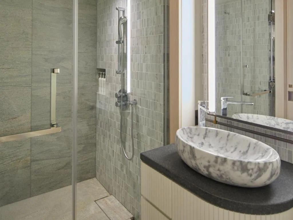 Badezimmer mit Regendusche und Marmorwaschbecken im Hotelzimmer.