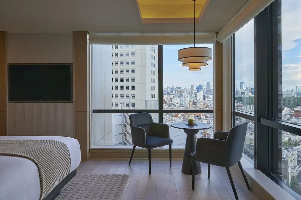 Geräumiges Zimmer mit Doppelbett und großen Fenstern mit Stadtblick