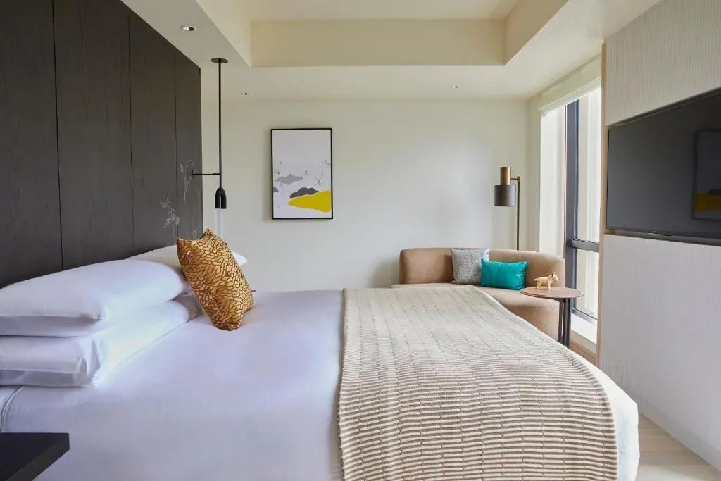 Helles Schlafzimmer mit beigem Sofa und dekorativen Kissen im Kimpton Shinjuku Tokyo.