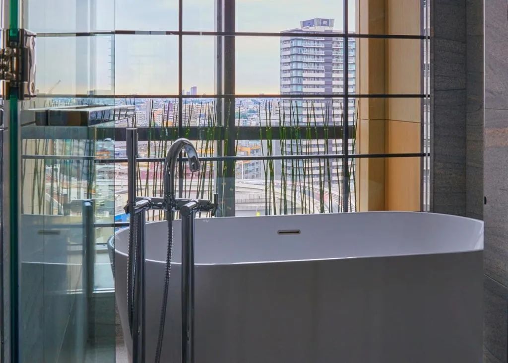 Freistehende Badewanne mit Stadtblick im Kimpton Shinjuku Tokyo Badezimmer.