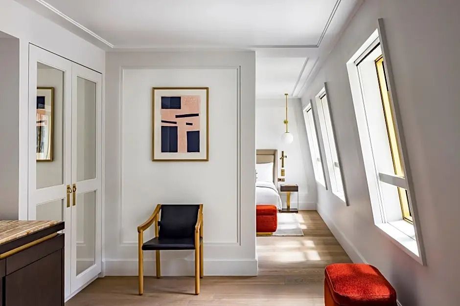 Helles Schlafzimmer mit künstlerischer Wanddekoration und Sessel.