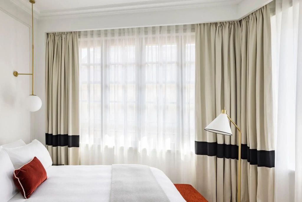 Helle Fensterfront mit Vorhängen und eleganter Stehlampe.