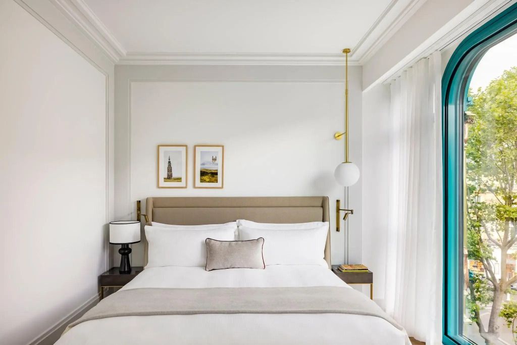 Helles Doppelzimmer mit beigem Bett, gerahmten Bildern und stilvollen Akzenten.