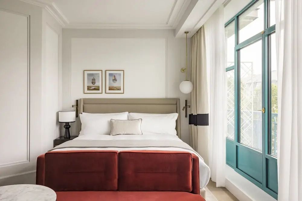 Doppelzimmer mit großem Bett, rotem Sofa und Blick auf den Balkon.