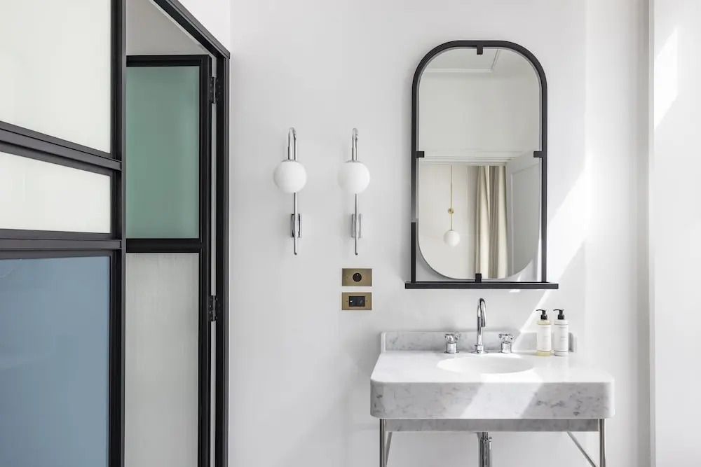 Badezimmer mit modernem Waschbecken, stilvoller Beleuchtung und großem Spiegel.