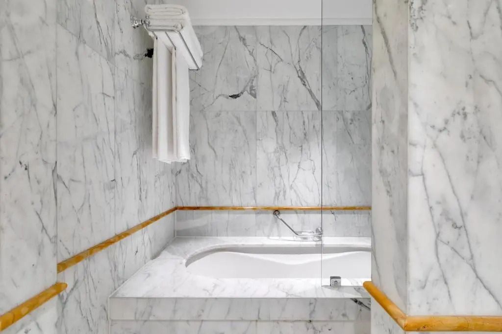 Geräumige Badewanne in einem Marmorbad mit eleganten Armaturen und Handtuchhalter.