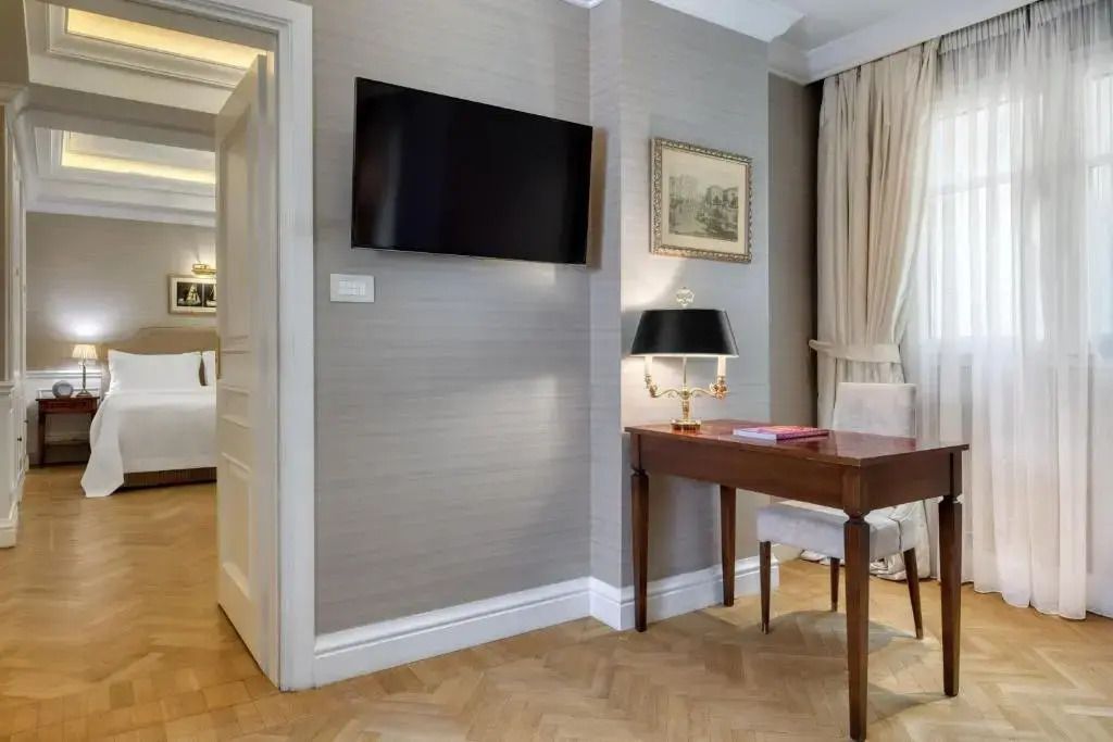 Hotelzimmer mit Schreibtisch, Fernseher und eleganter Innenausstattung.