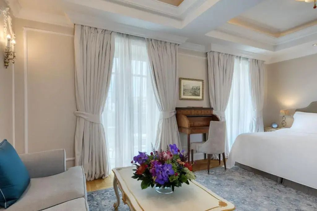 Deluxe Zimmer mit Sofa und Schreibtisch vor bodentiefen Fenstern