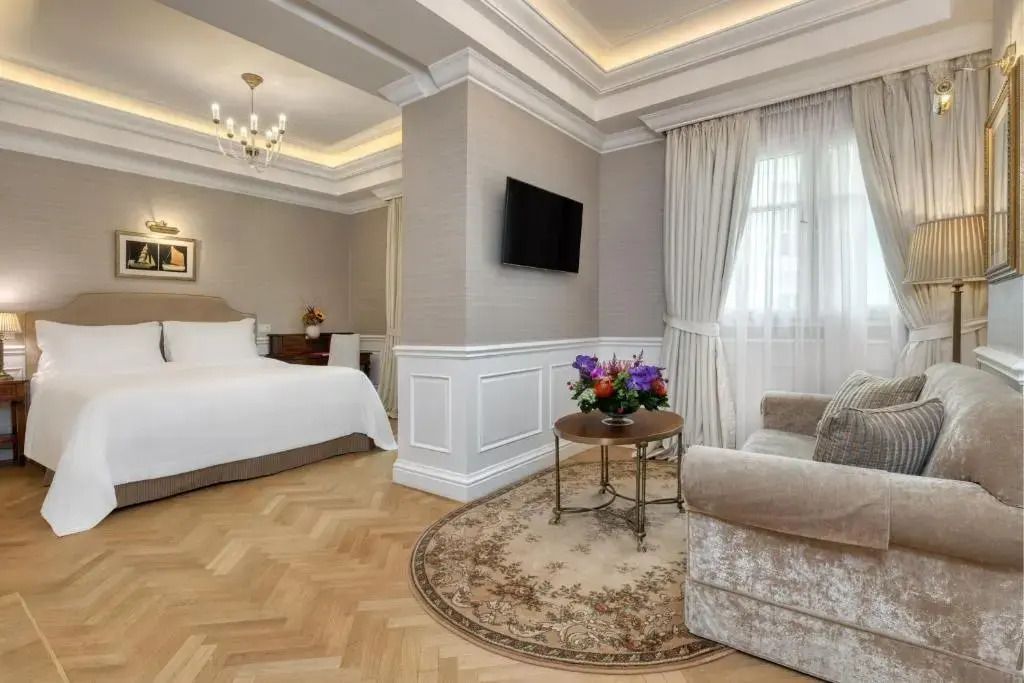 Schlafbereich einer Junior-Suite mit Doppelbett und Sitzbereich neben großem Fenster